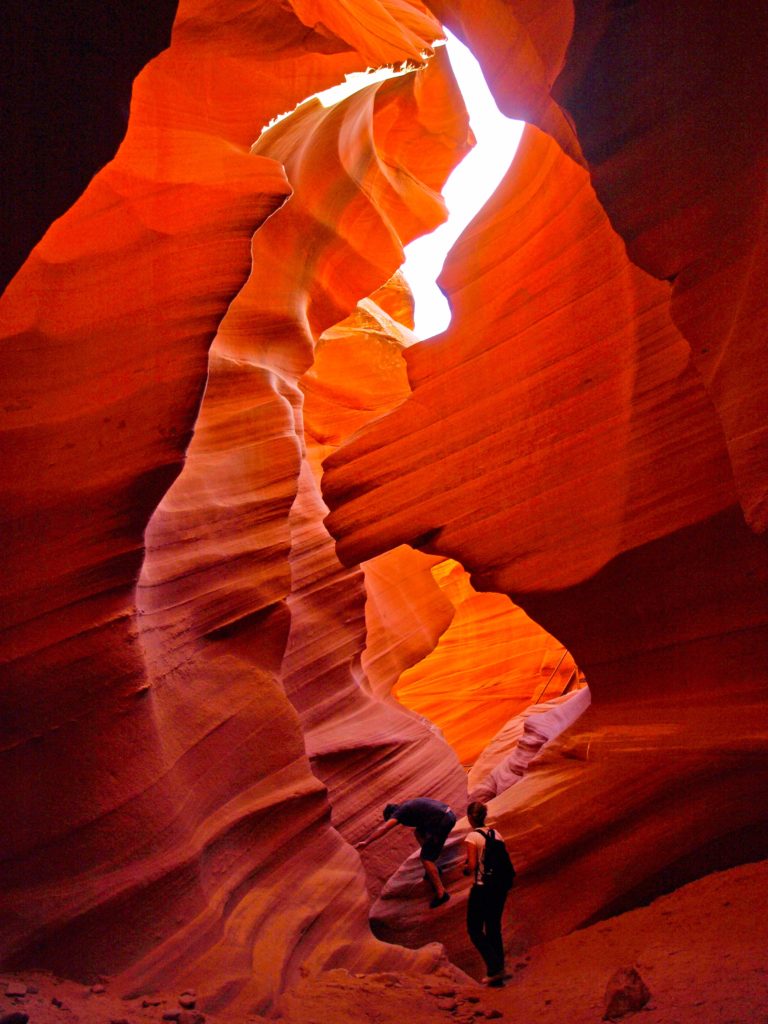 Tow people are climbing through Lower Antelope Canyon